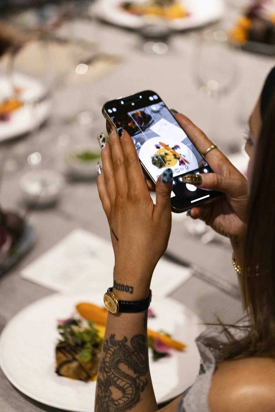 A guest photographing her course at the See Dining Differently launch