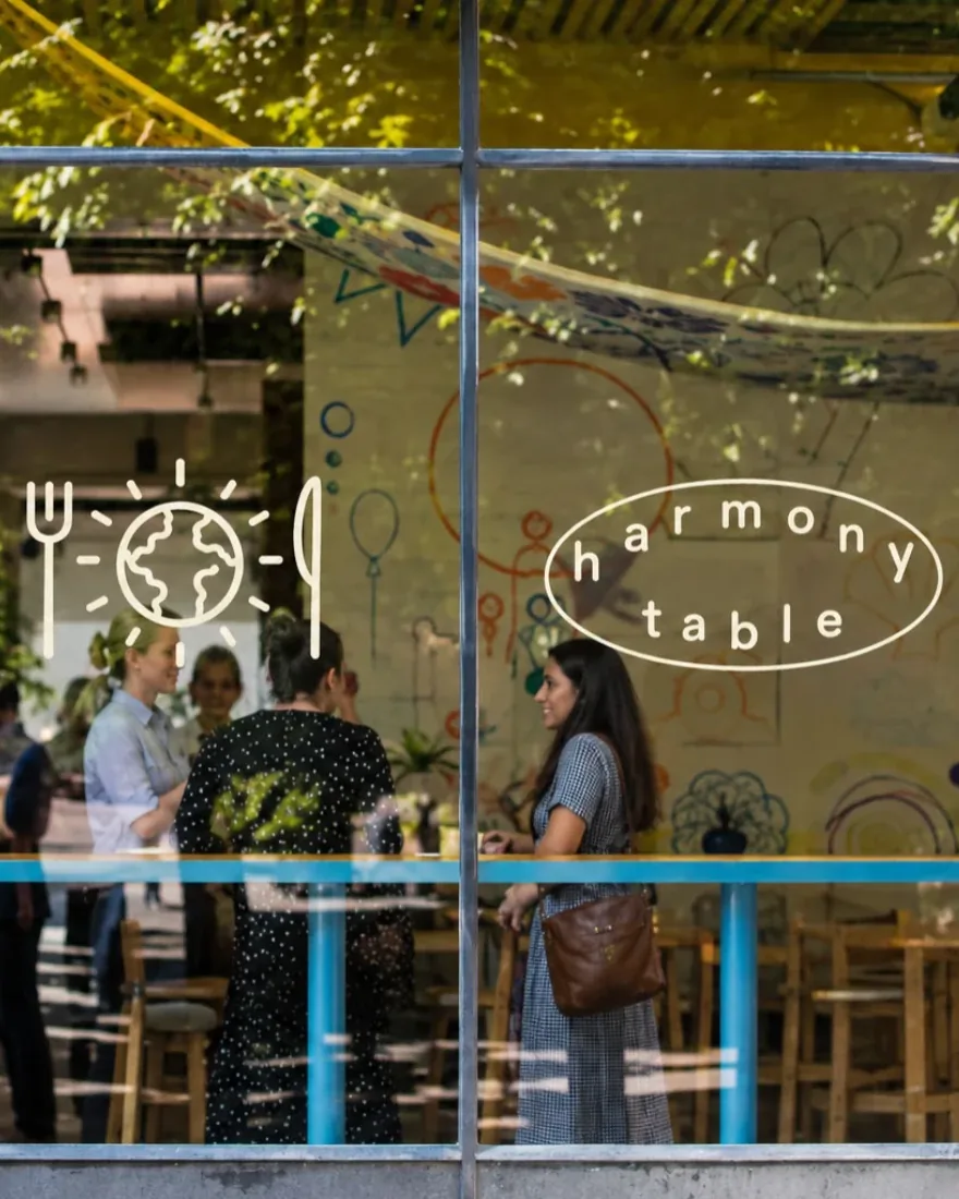 Harmony Table storefront window decal with guests gathered inside